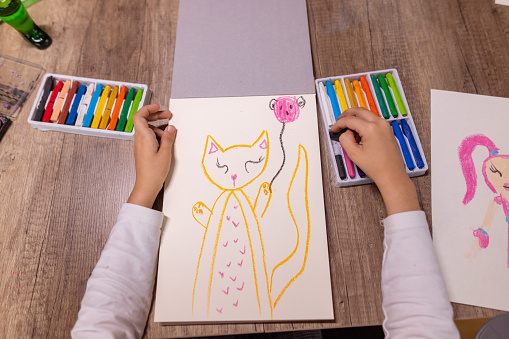 A little girl draws a cat on paper