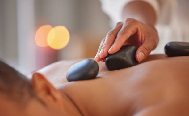 spa, massage homme et pierre pour se détendre, bien-être et santé pour les soins du corps, la paix ou les soins holistiques. homme, gentleman ou allongé sur la table dans un complexe de luxe, zen ou thérapie pour les soins de la peau avec des pierres - lastone therapy spa treatment massaging massage therapist photos et images de collection