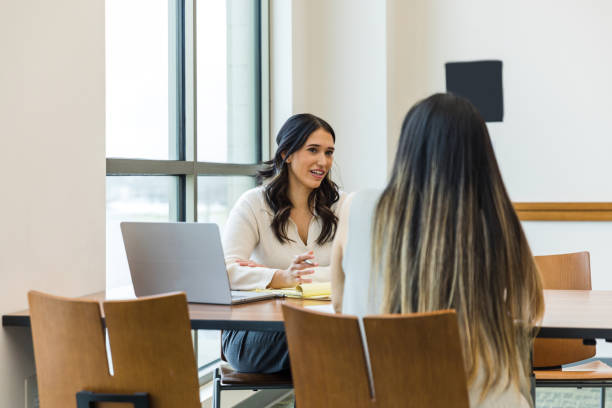 Female business owner asks unrecognizable female job applicant questions The young adult business owner gestures as she asks the unrecognizable female job applicant questions during the interview. College applicants stock pictures, royalty-free photos & images