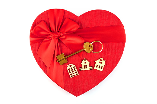 Heart shaped golden key is inside of a red folding heart shape on white background. Horizontal composition with  copy space.