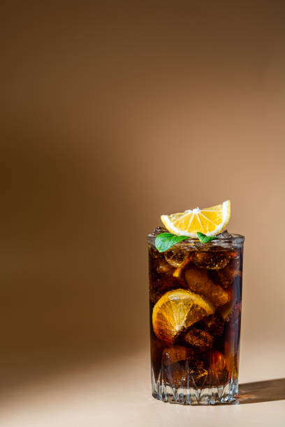 Cuba Libre cocktail Cuba Libre in a glass with brown rum, cola, mint and lemon on light background with natural light and shadows. Cuba Libre or long island iced tea cocktail with strong drinks cuba libre stock pictures, royalty-free photos & images