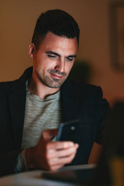 istock Smiling Businessman Using A Mobile Phone At Home At Night 1470741775