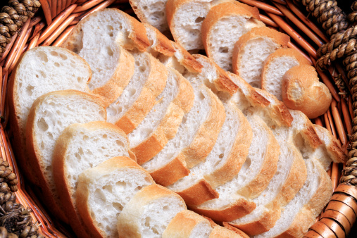 A loaf of thin sliced white bread inside a basket made from heath.