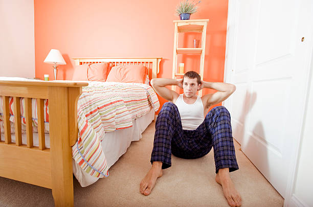 Homem a fazer abdominais no Quarto de Dormir - fotografia de stock