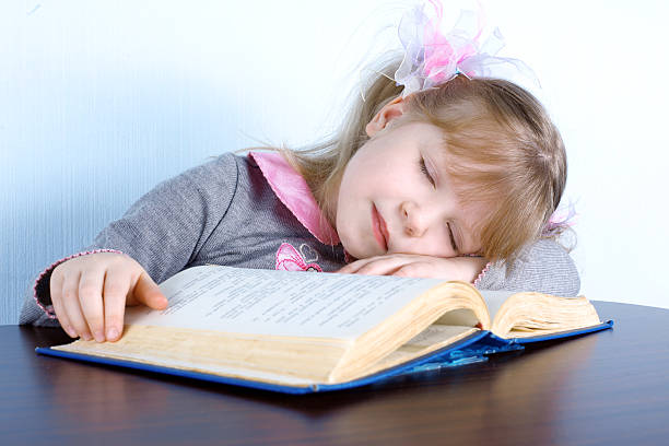 istock girl sleeping on book at table 147074273