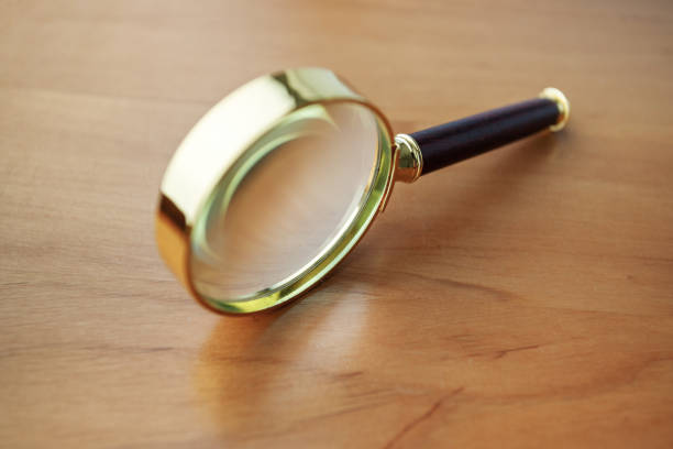 A magnifying glass with a gold handle. The handle is made of wood and the glass is clear