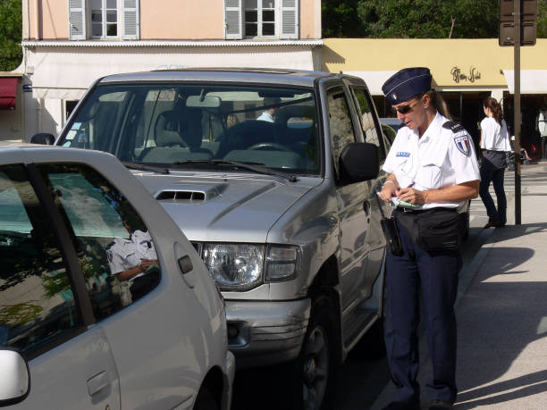 Female police officer fining a car in St. Tropez, France stock photo