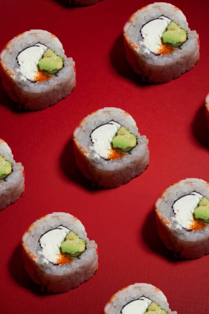 istock shrimp sushi rolls pattern with a green avocado and cheese on a red background 1470744489