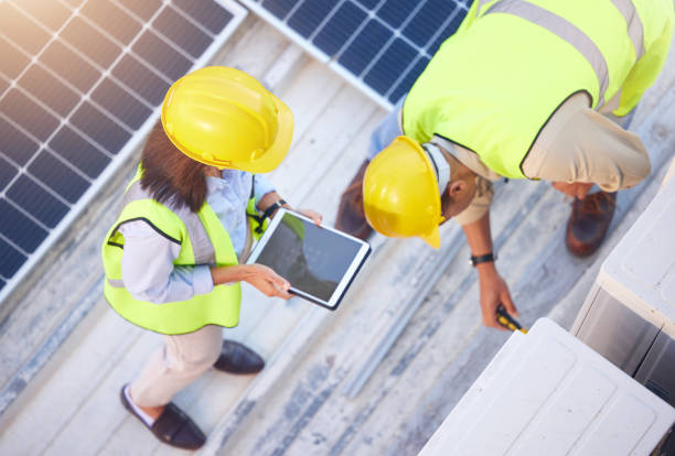 Top view, teamwork and engineers with tablet on solar roof for maintenance, inspection or installation. Solar energy, renewable energy and man and woman with tech for planning service of solar panels