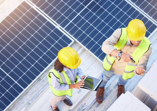 istock Top view, teamwork and engineers with tablet on solar roof for maintenance, inspection or installation. Solar energy, renewable energy and man and woman with tech for planning service of solar panels 1470745356