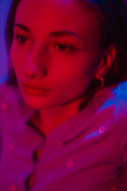 istock Young female model in a dark colorful lit studio environment posing against the wall and floor 1470746684