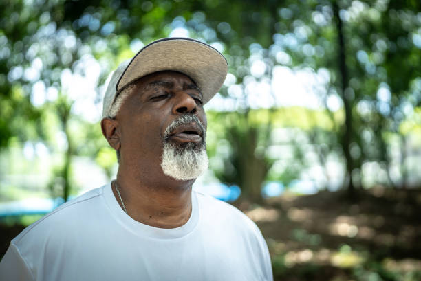 Senior man doing breathing exercise in the park Senior man doing breathing exercise in the park exhaling stock pictures, royalty-free photos & images