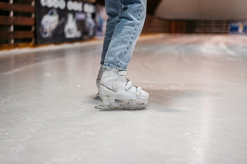 Low section of a young woman ice skating in an ice skating rink indoors.
