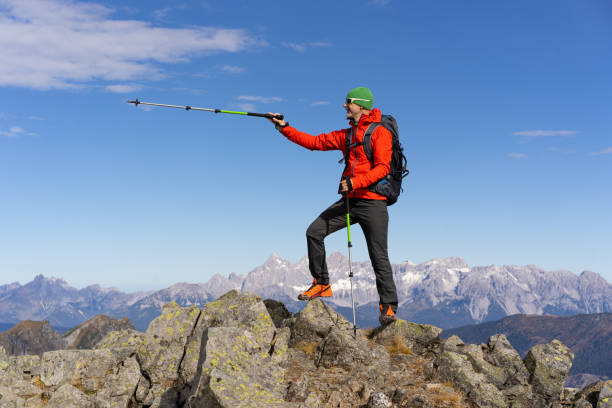 istock Mountaineer man standing on mountain peak pointing with hiking pole 1470751397