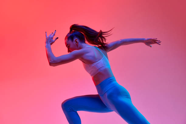 istock Speed up. Young girl, professional runner athlete in uniform training, running over pink studio background in neon light. Concept of sport. health and strength 1470753479