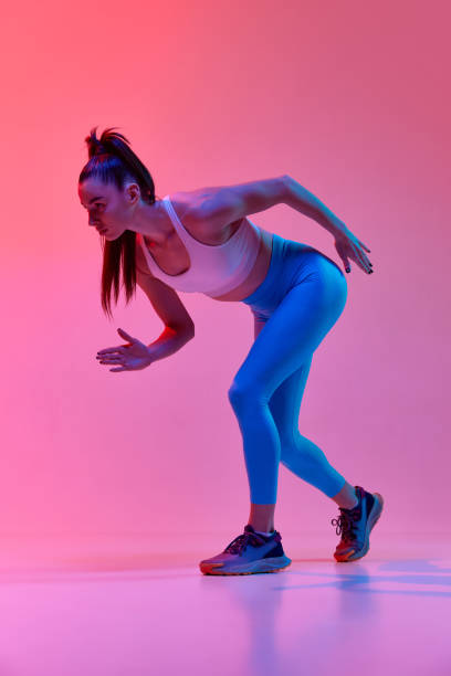 istock Young sportive girl, professional runner, athlete warming up before run over pink studio background in neon light. Concept of sport. health and strength 1470753486