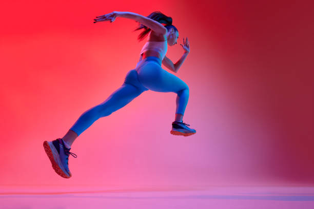 istock Bottom view. Young girl, professional runner athlete in uniform training, running over pink studio background in neon light. Concept of sport. health and strength 1470753529