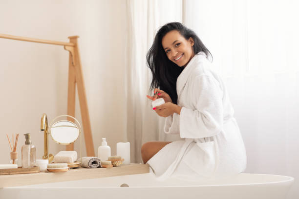 istock Happy Mixed Lady Opening Moisturizer Jar Posing In Modern Bathroom 1470753865