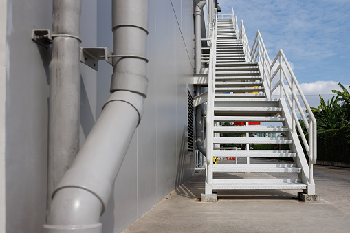 white fire exit stair of large building against blue sky. outdoor metal stair step. fire escape stair way.