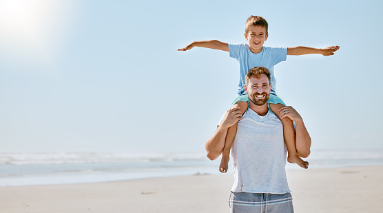 Father with boy on neck, portrait and beach for bonding, vacation and spend quality time together. Family, man and male child travelling, happiness and loving on seaside, holiday and coastline trip.