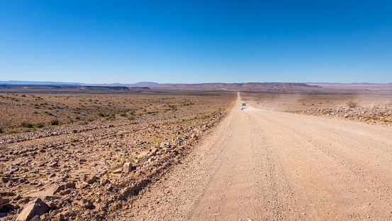 Panoramic view of the desert road with rocky landscape on the background in Spitzkoppe, Namibia