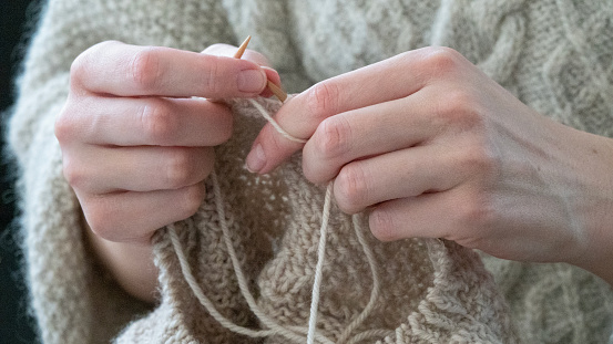 Female hands knitting in cose-up. Girl relaxing knitting a warm sweater.