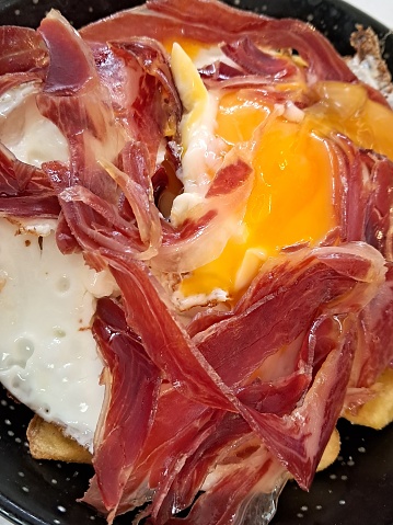 A delicious eggs, potatoes and ham inside a pan.