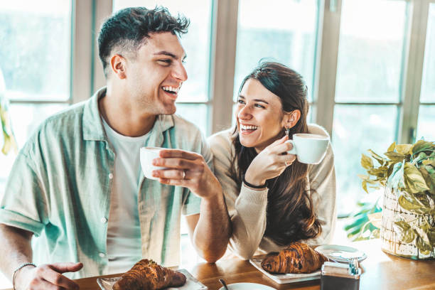 glückliches paar genießt das frühstück und trinkt kaffee in der bar-cafeteria - lifestyle-konzept mit verliebten männern und mädchen, die sich im restaurant im stadtzentrum verabreden - coffee couple italy drinking stock-fotos und bilder