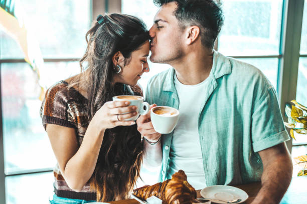 happy couple enjoying breakfast drinking coffee at bar cafeteria - life style concept with guy and girl in love having date moment sitting at restaurant in the city centre - espresso women cup drink imagens e fotografias de stock