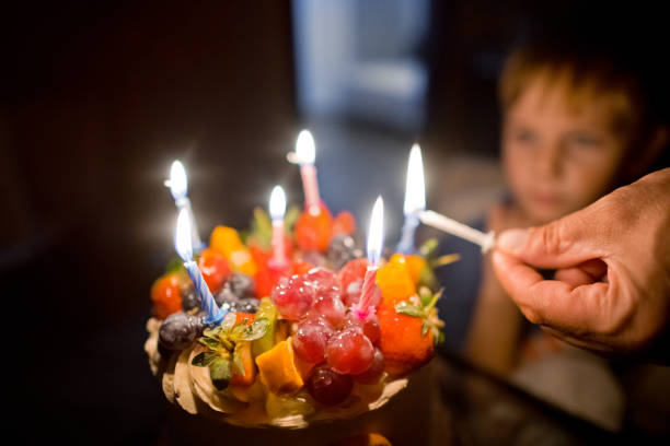 Over-the-shoulder view of a senior man holding a birthday cake.