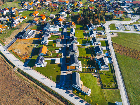 Aerial view, drone flying over new housing development in the country side. Family homes in the suburbs surrounded with forest and green fields.