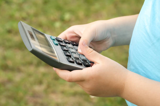 menina anônima em idade escolar, criança usando uma calculadora segurando-a nas mãos, close-up objeto, uma pessoa. stem, matemática, aprendizagem matemática, educação, assunto educacional, crianças inteligentes, ciências - skill child mathematics physics - fotografias e filmes do acervo