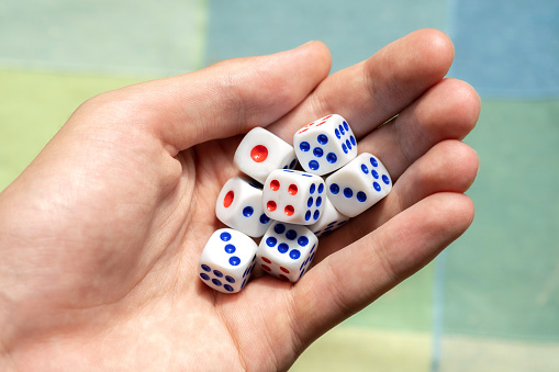 Man holding a few small game dice showing different numbers in hand, group of objects closeup. Math randomness, entropy, probability and statistics, education subject abstract concept, one person