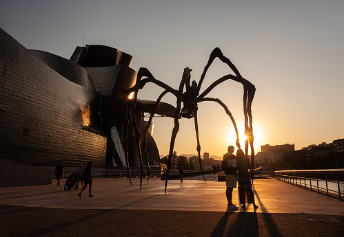 Bilbao, Spain - August 02, 2022: The Spider, sculpture of Louise Bourgeois titled Mamam next to the Guggenheim Museum at sunset