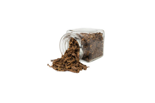 Valerian herb root falling from glass jar isolated on white background. Valeriana officinalis. used in herbal medicine as a tranquillizer and to treat insomnia, anxiety, hypertension, pain relief. raíz de hierba valeriana que cae de un frasco de vidrio aislado sobre fondo blanco. valeriana officinalis. se utiliza en la medicina herbal como tranquilizante y para tratar el insomnio, la ansiedad, la hipertensión, el alivio del dolor.