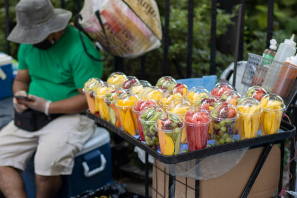Mexican Fruit Cups Vendor New York, NY, USA - July 4, 2022: A street vendor sells Mexican fruit cups (vasos de fruta, in Spanish) in Lower Manhattan, New York City, on a summer day. Selective focus on the fruit cups. fruit cart vendor stock pictures, royalty-free photos & images