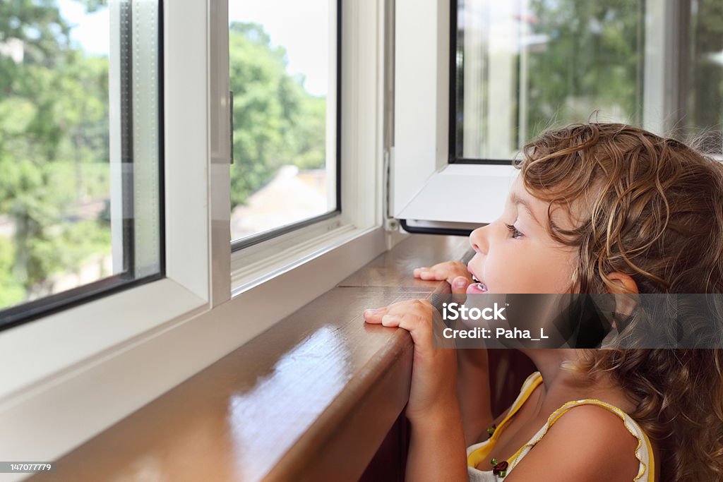 Pretty smiling little girl on balcony Pretty smiling little girl on balcony, look from window Child Stock Photo