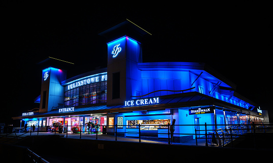 Felixstowe, Suffolk, UK: The entrance to Felixstowe pier at night illuminated with dark blue lights.