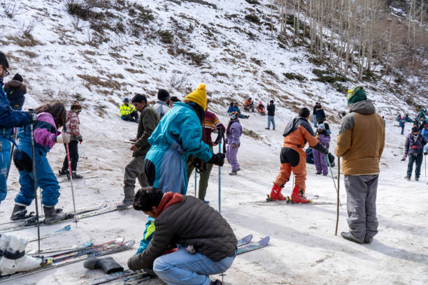 Panning shot of crowd of people in winter wear playing in snow, sking, sliding, at snow point in lahul, manali solang a popular tourist spot during winters stock photo