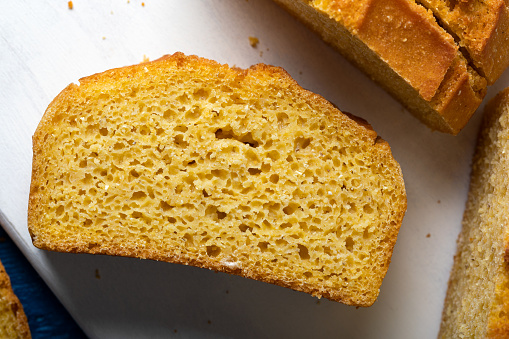 Beautiful homemade yellow,  sliced cornbread loaf. Freshly baked cornbread on wooden background.