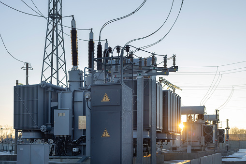 High-voltage transformer substation in winter at dawn. High voltage equipment. Energy transfer technology.
