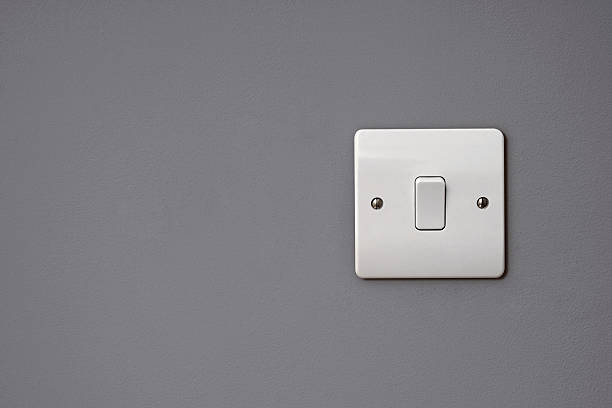 Close-up of white square light switch on the wall Light switch on clean grey wall – space for copy light switch photos stock pictures, royalty-free photos & images