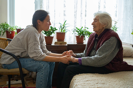 Volunteer woman caretaker talking with senior woman.