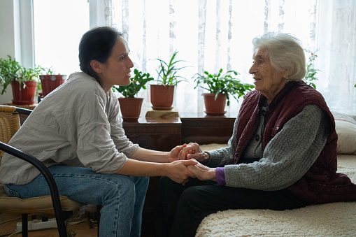 Volunteer woman caretaker talking with senior woman.