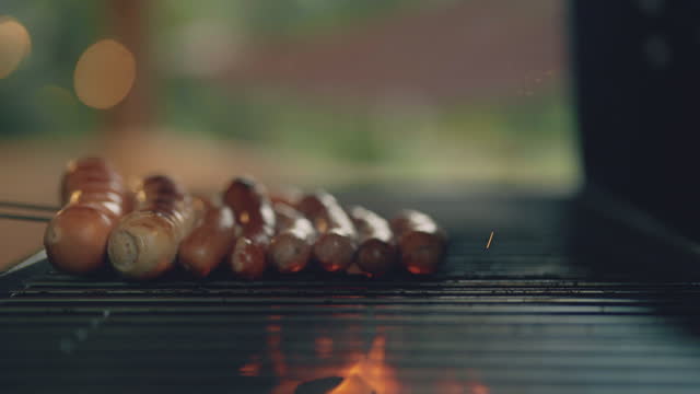 Close-up of Cooking hotdogs on a flaming barbecue grill.
