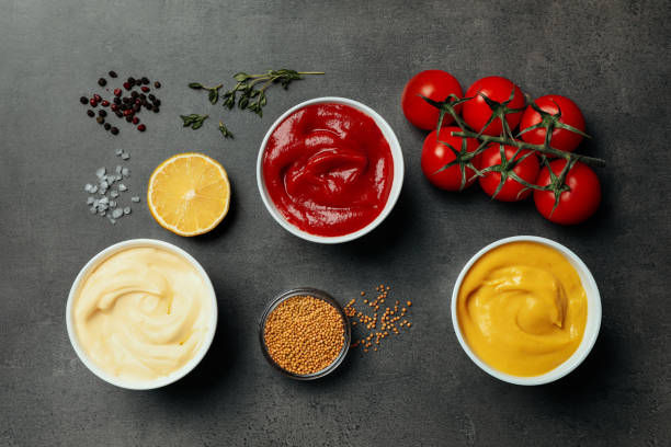 istock Flat lay composition with ketchup, mustard, mayonnaise and ingredients on grey table 1470797295