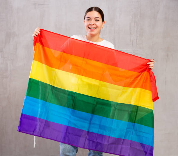 istock Smiling young woman holding LGBT flag 1470797513