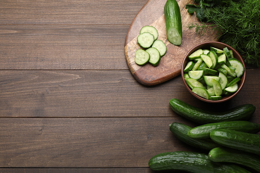 Fresh ripe cucumbers and dill on wooden table, flat lay. Space for text