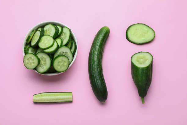 Fresh ripe cucumbers on pink background, flat lay