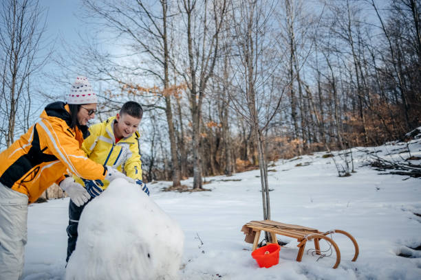 istock Mother and son playing on snow making snowman 1470800721